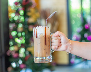 Hand holding ice coffee on bokeh light background,