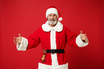 Fototapeta na wymiar Elderly gray-haired bearded mustache Santa man in Christmas hat posing isolated on red background. New Year 2020 celebration concept. Mock up copy space. Demonstrating size with horizontal workspace.