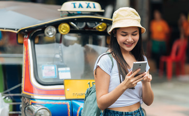 Happy traveller woman using smartphone on street in Bangkok Thailand.