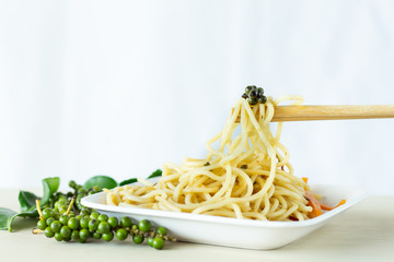 Pepper beads on spaghetti and chopsticks on white background,