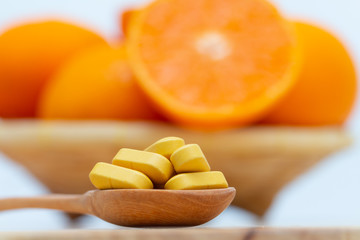 Medicine in wooden spoon on blurred orange slice  background,