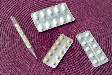 Different tablets, pills in foil blister packs, medications drugs on red background - 298636828