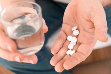 Elderly man taking medicine at home, closeup