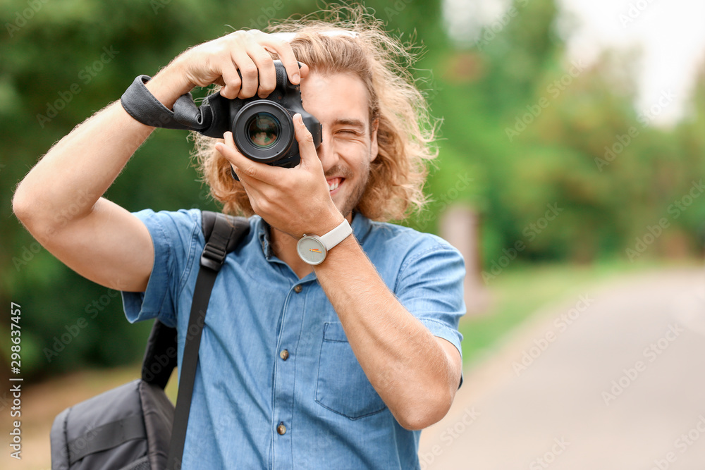 Wall mural young male photographer with camera outdoors