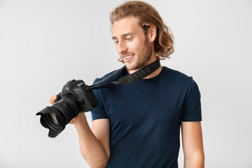 Young male photographer on light background