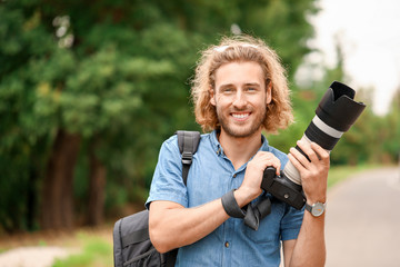 Young male photographer with camera outdoors - obrazy, fototapety, plakaty