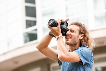 Young male photographer with camera outdoors