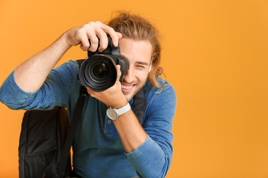 Young male photographer on color background