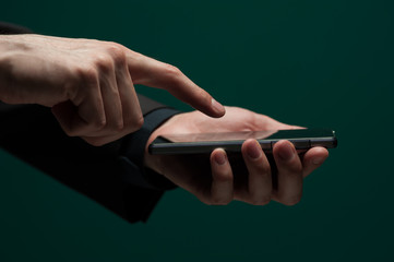 Man in a dark shirt and jacket holds a smartphone