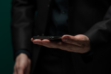 Man in dark shirt and jacket holds smartphone