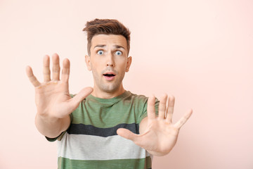 Shocked young man showing STOP gesture on color background
