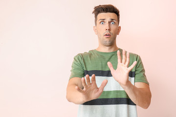 Shocked young man on color background