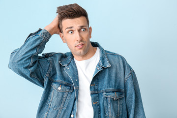 Shocked young man on color background