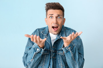 Shocked young man on color background