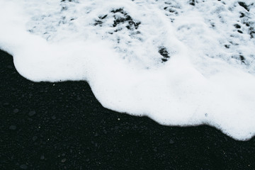 White ocean water and black sand beach in Iceland