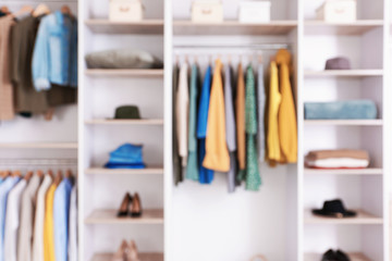 Big wardrobe with clothes in dressing room, blurred view