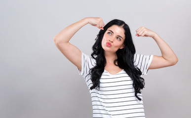 Fototapeta premium Powerful young woman in a success pose on a gray background