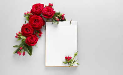 Notebook and beautiful roses on light background