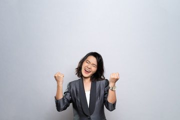 Happy woman make winning gesture isolated over white background