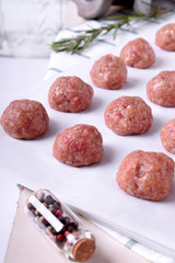 Raw meatballs on the piece of parchment ready to be cooked