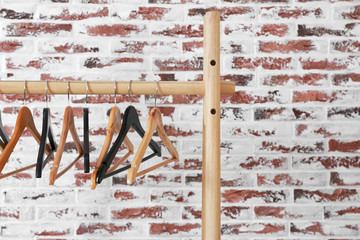 Rack with clothes hangers on brick background