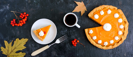 Piece of traditional homemade pumpkin pie and a cup of coffee on a black background. Healthy food,...