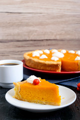 Piece of traditional homemade pumpkin pie and a cup of coffee on a black background. Healthy food, dessert for gourmets. Thanksgiving theme. Traditional autumn baking.