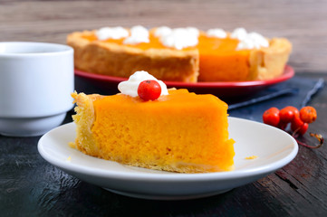 Piece of traditional homemade pumpkin pie and a cup of coffee on a black background. Healthy food, dessert for gourmets. Thanksgiving theme. Traditional autumn baking.