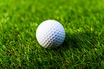 Golf ball on the green,Green grass with golf ball close-up in soft focus at sunlight. Sport playground for golf club concept - wide landscape as background for your lettering about golf playing.