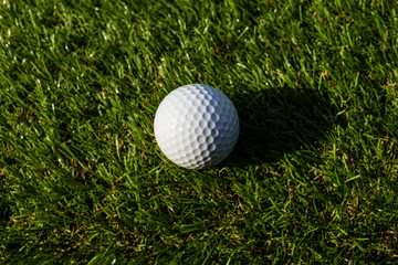 Golf ball on the green,Green grass with golf ball close-up in soft focus at sunlight. Sport playground for golf club concept - wide landscape as background for your lettering about golf playing.