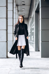 Portrait of a full-length girl on the street in autumn. Young adult girl in an elegant coat...