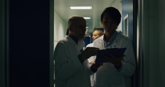 The scientists are discussing a project of a research of new pharmaceutical medicaments creation during walking in a scientific center ward.