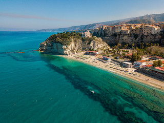 Aerial view of a beach with umbrellas and bathers. Promontory of the Sanctuary of Santa Maria dell'Isola, Tropea, Calabria, Italy.