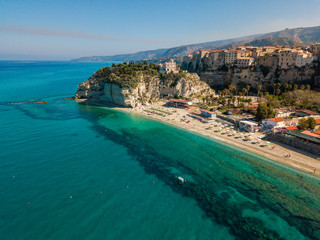 Fototapeta premium Aerial view of a beach with umbrellas and bathers. Promontory of the Sanctuary of Santa Maria dell'Isola, Tropea, Calabria, Italy.