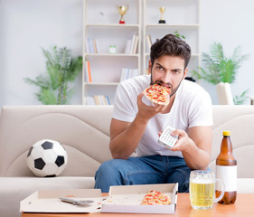 Man eating pizza having a takeaway at home relaxing resting