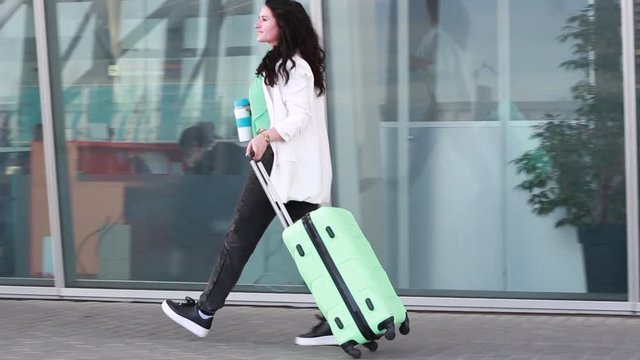 Businesswoman goes with a suitcase at the airport. Dark-haired woman. The latest technology.Girl