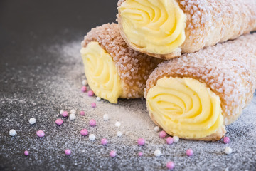 Puff pastry horns filled with vanilla cream, powdered sugar and topping