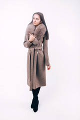 Studio shooting demi-season clothing. Young adult girl in an elegant coat on a white background. Promotional women's coat. Young fashionable woman in a stylish woolen autumn and spring coat.