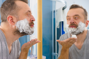 Guy shaving his beard in bathroom