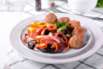 Multicolored pasta and meatballs garnished with parsley served on the white ceramic plate