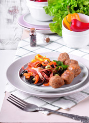 Multicolored pasta and meatballs garnished with parsley served on the white ceramic plate