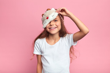 cheerful happy smiling girl taking off sleeping mask, close up portrait, isolated pink background,...