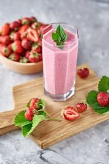 Strawberry milk shake in a glass jar and fresh strawberries with leaves