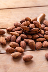 Close up raw peeled almonds seed in wood spoon on wooden background.