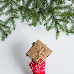 Woman in the winter gloves packing gift in a box of kraft paper on white wood table. Christmas tree, spruce branches. concept. New Year. concept. Flat lay, Instagram