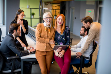Happy business women working together online on a digital tablet at the office
