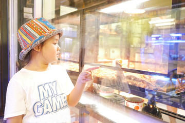 Asian girl is looking at a chameleon that is being sold in a large market in Asia.