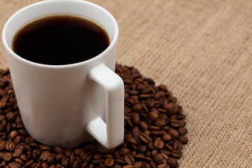 cup of coffee with beans on wooden table