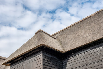 Exterior view of a large, timber built farm building with a thatched roof. The wooden entrance...