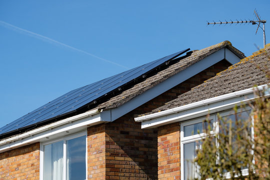 Isolated, Shallow Focus Of Newly Installed Solar Panels On A Detached House. Also In View Is Another House With Solar Panels Installed To Help Reduce Electric Utility Bills.